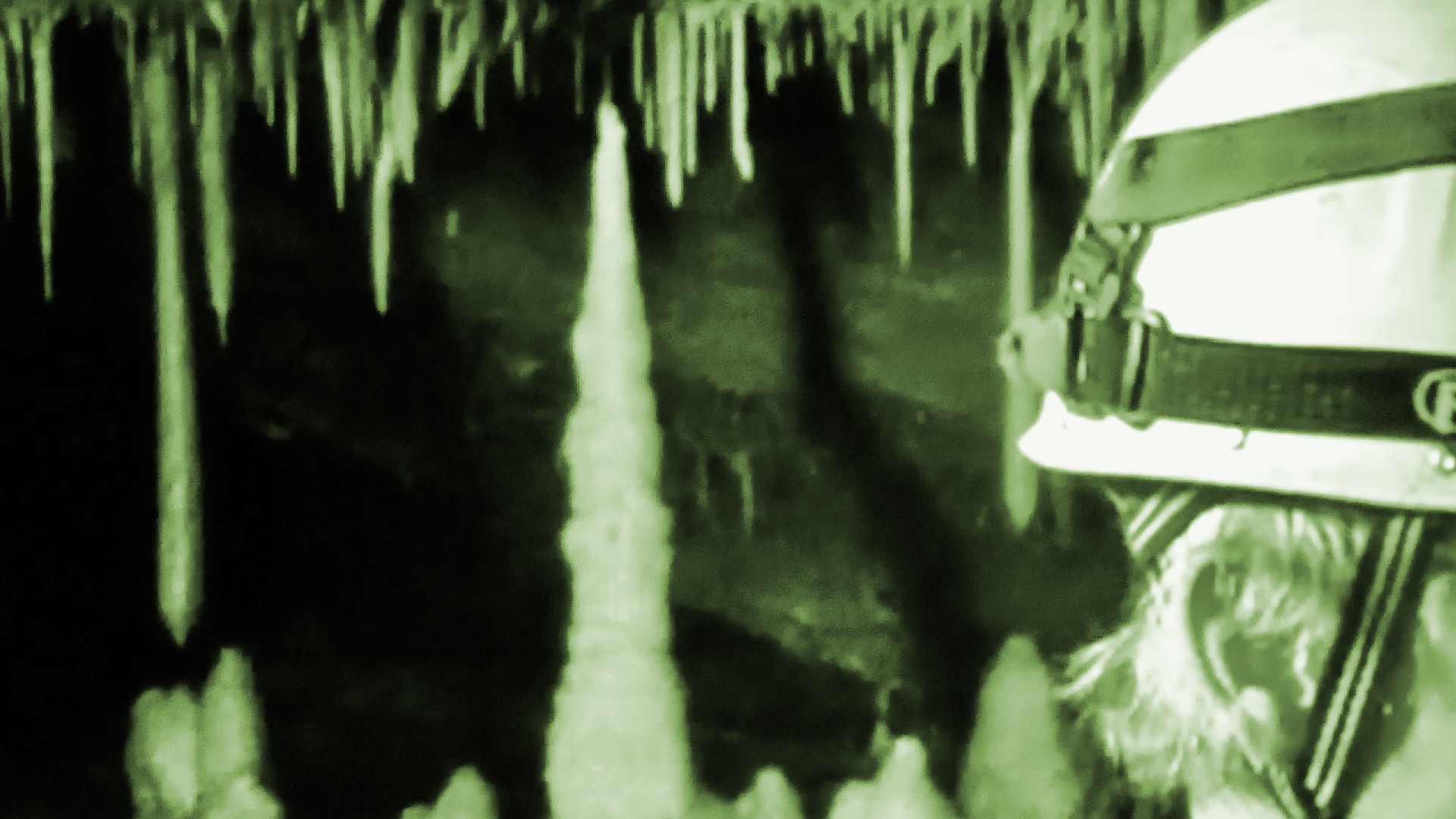 Person mit Helm, dahinter Tropfsteine